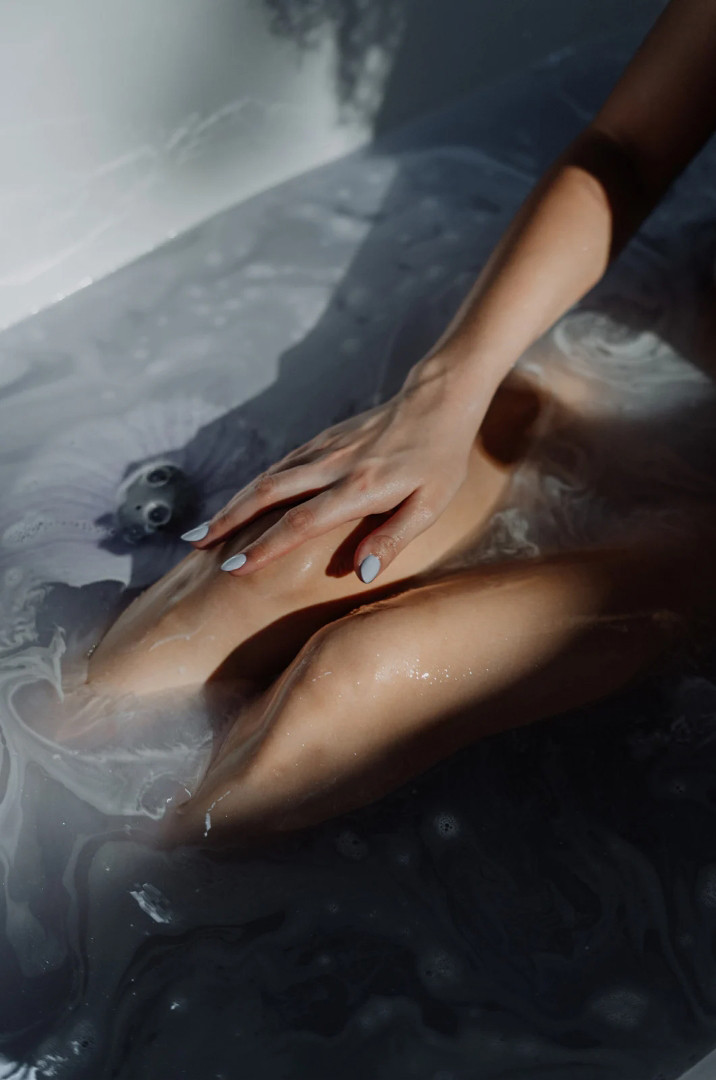woman stroking legs in shower